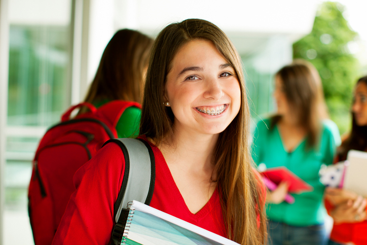 Teen Girl Smiling Looking at Camera Holding Books